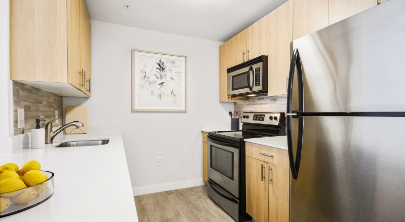 Kitchen at James Court featuring natural cabinetry, stainless steel appliances and quartz counters.