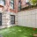 Fenced pet play area with turf grass, a tennis ball wall, and red fire hydrant toy 