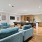 Community lounge at our apartments for rent in Boston MA featuring four blue armchairs, a complimentary coffee station, and a shuffleboard table 